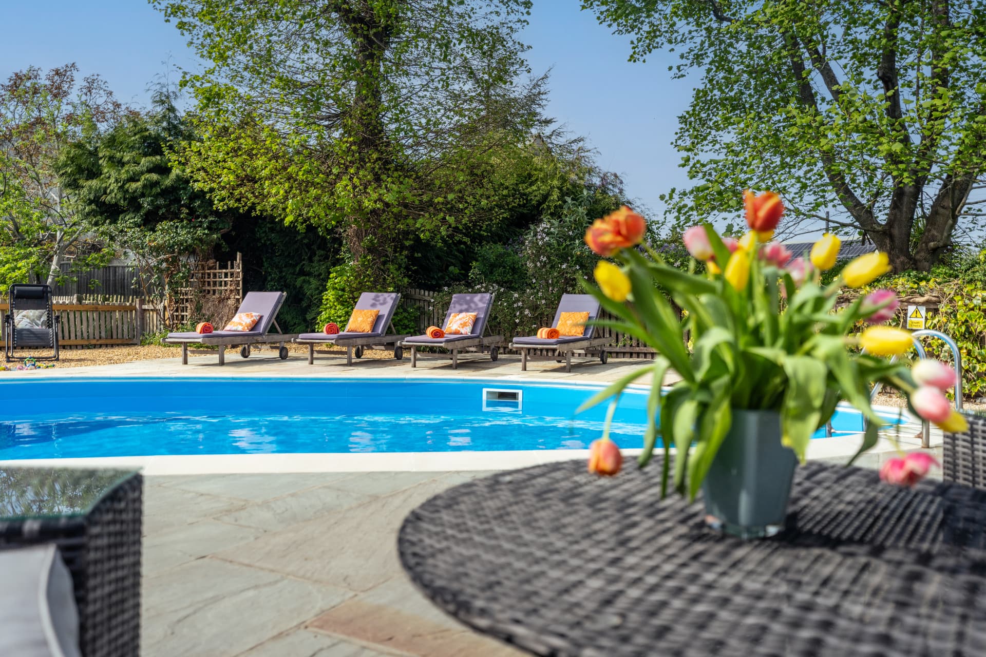 The pool terrace at Little Upton with sun loungers, outdoor seating and flowers